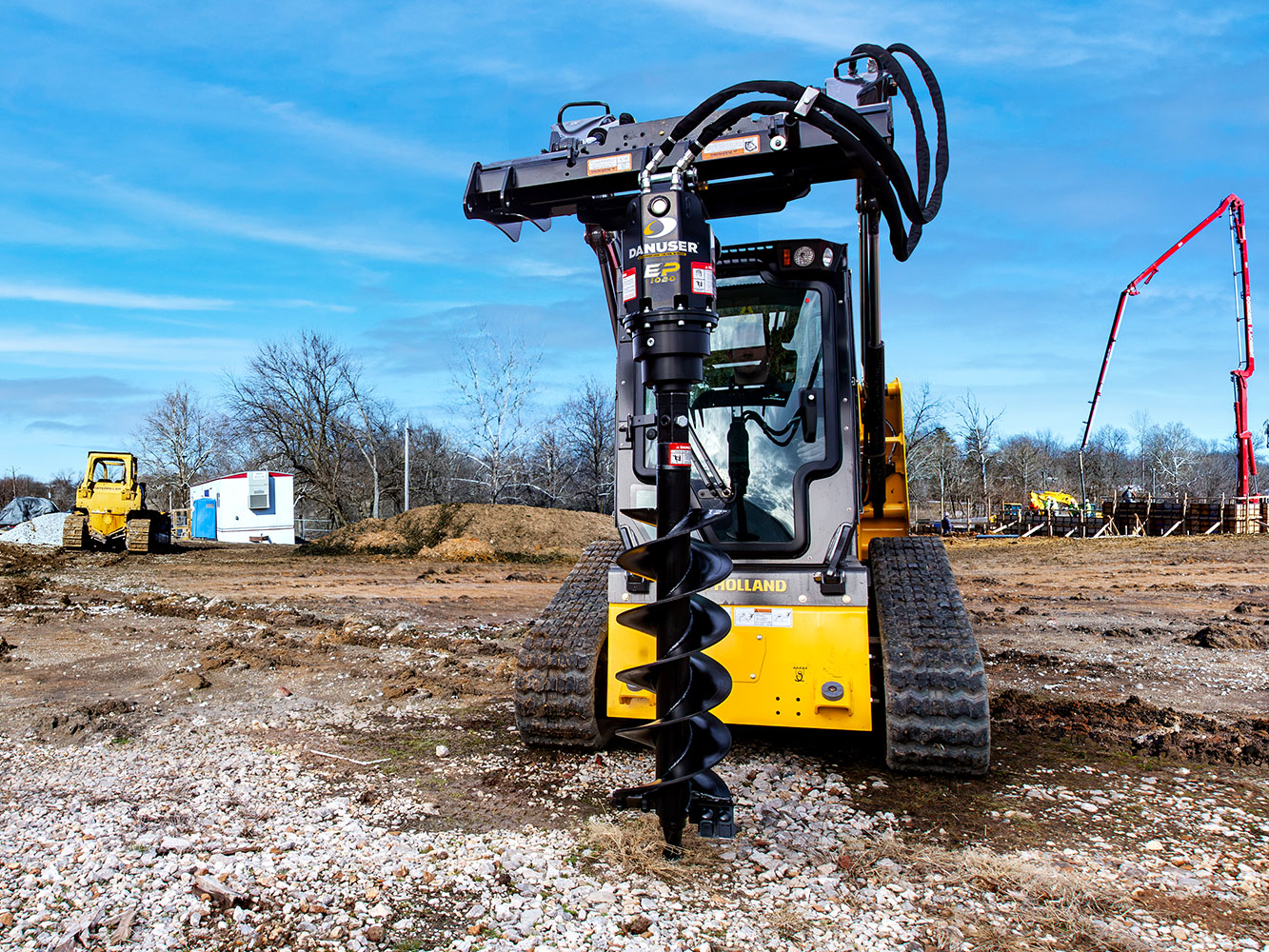 Image showing Danuser EP 1020 Auger Drive on New Holland Skid Steer at construction site with gravel and equipment in background