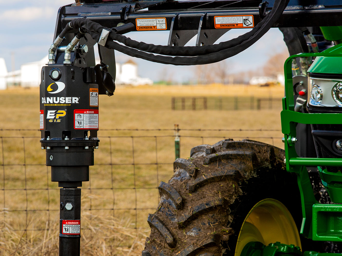 Image showing close-up of Danuser EP 615 Auger Drive on John Deere tractor with barbed wire fence and open field in background