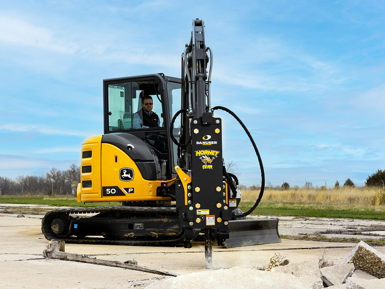 Image showing Danuser Hornet T8-RR post driver on Mini John Deere 50P Excavator breaking up concrete near open field