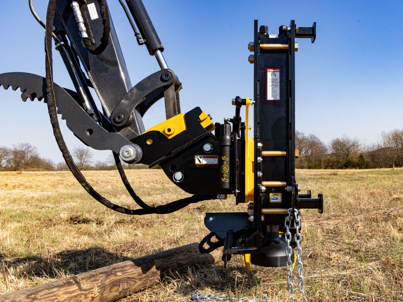 Image showing Danuser Hornet T8-RR post driver on Mini John Deere 50P Excavator close-up side view with wood post on ground in open grassy field