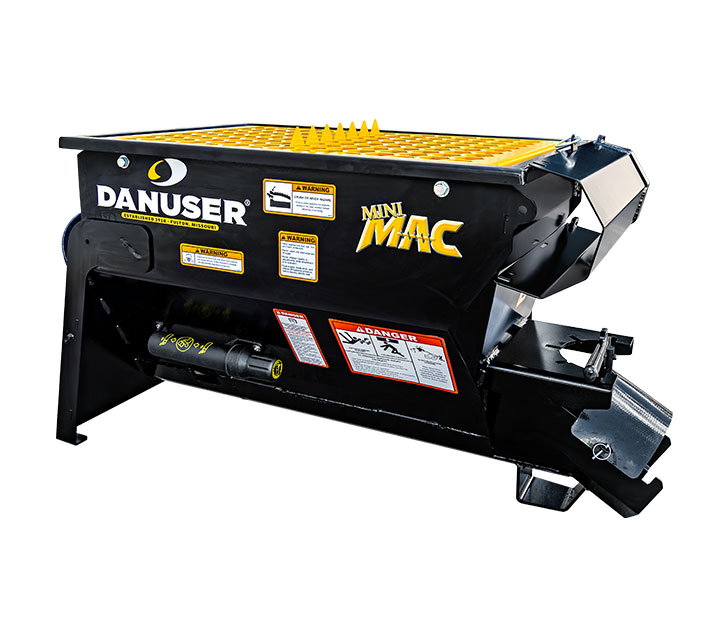 Danuser Mini MAC material handling bucket in black with yellow accents, featuring a spiked yellow grate cover, hydraulic components, and attachment mechanism for machinery.