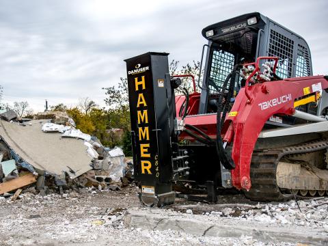 A red Takeuchi skid steer equipped with a Danuser Hammer CB40 hydraulic breaker attachment at a demolition site, surrounded by rubble and broken concrete.